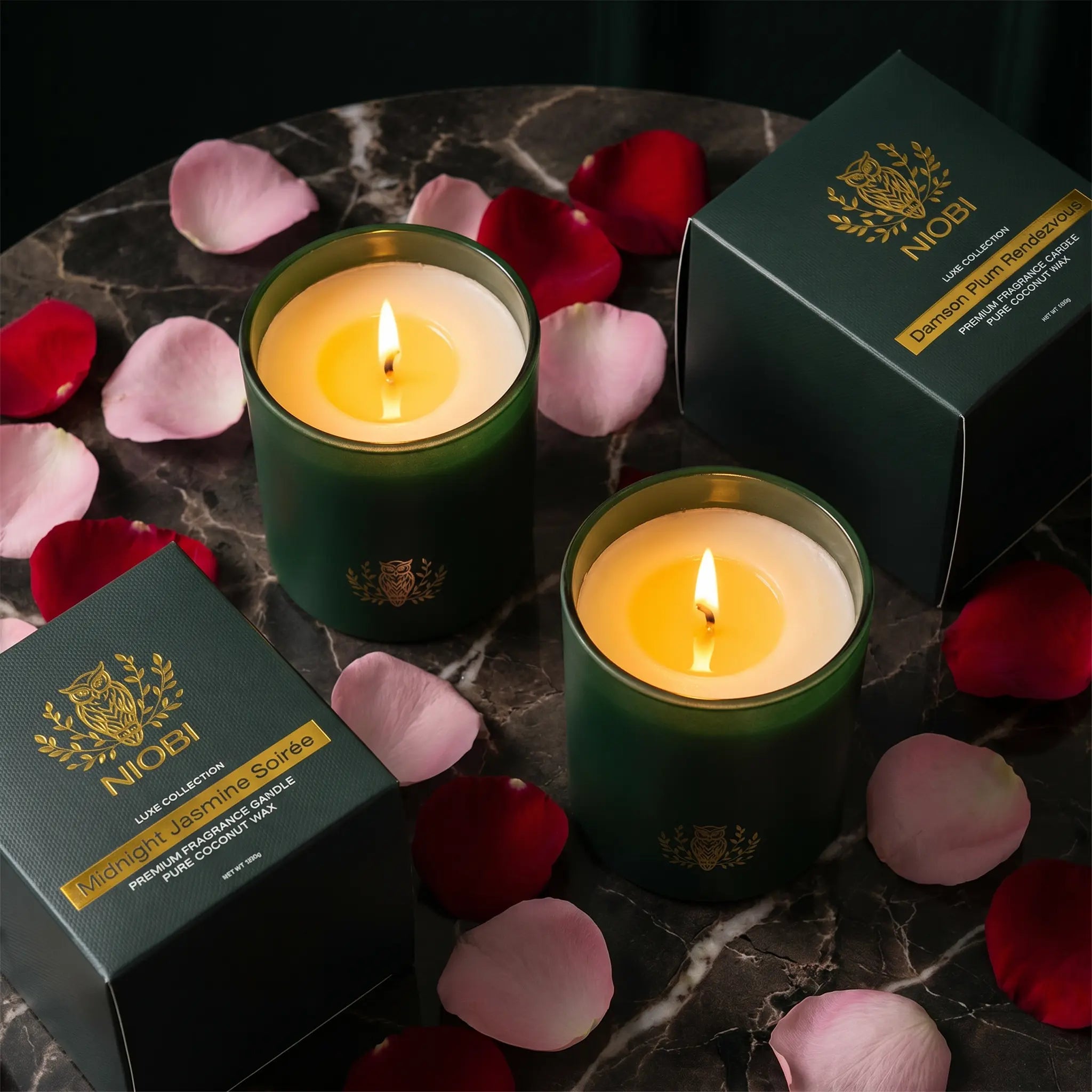 NIOBI Ритуал за двама запалени свещи Midnight Jasmine Soirée и Damson Plum Rendezvous с кутии и червени и розови листенца в романтична атмосфера